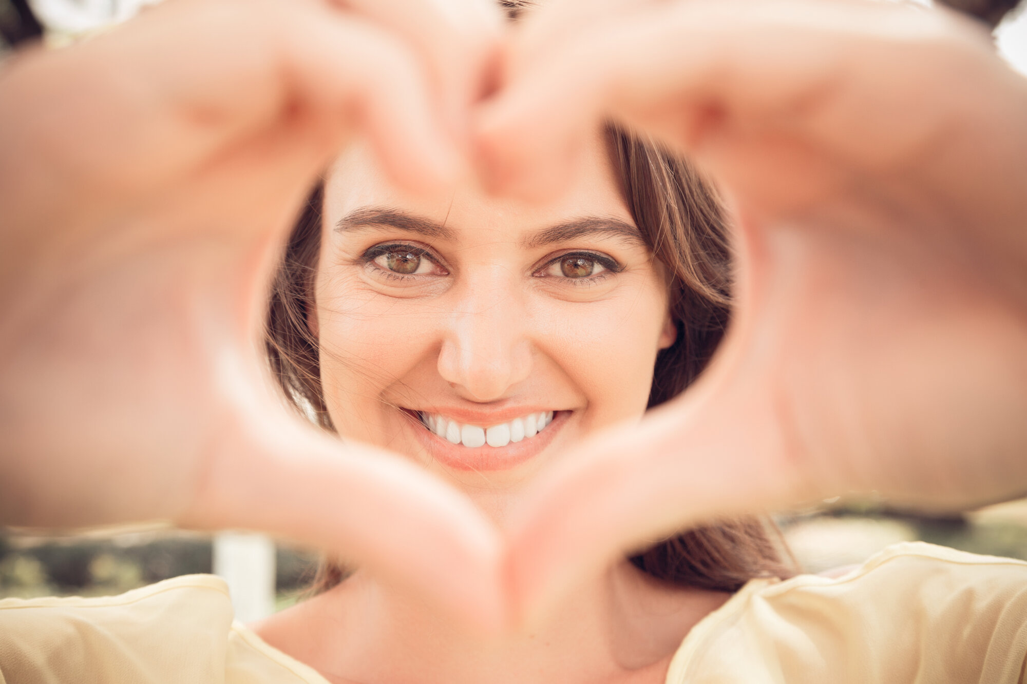 photo of a woman smiling and making a heart shape